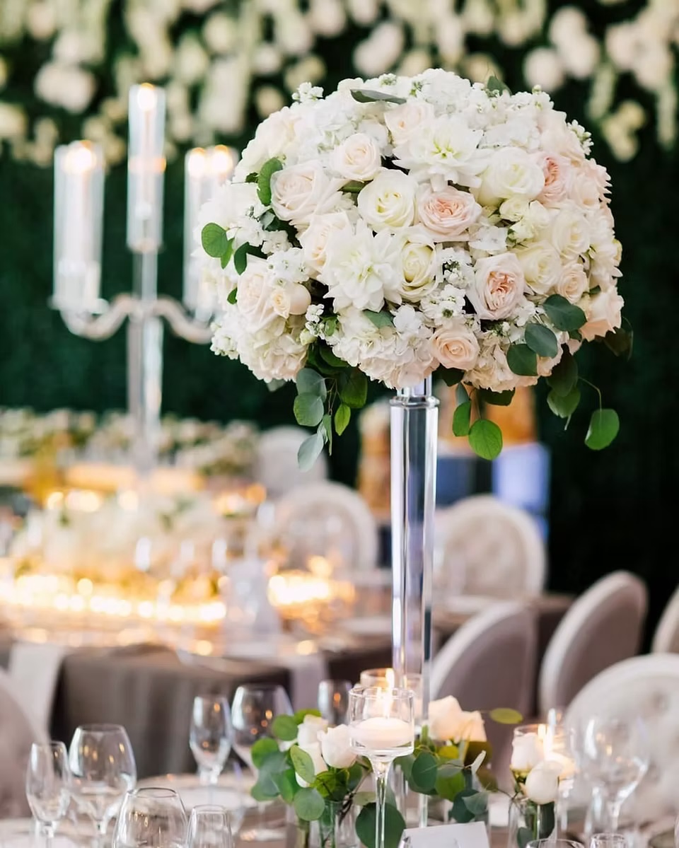 White floral centrepiece and candlelight against a garden green backdrop