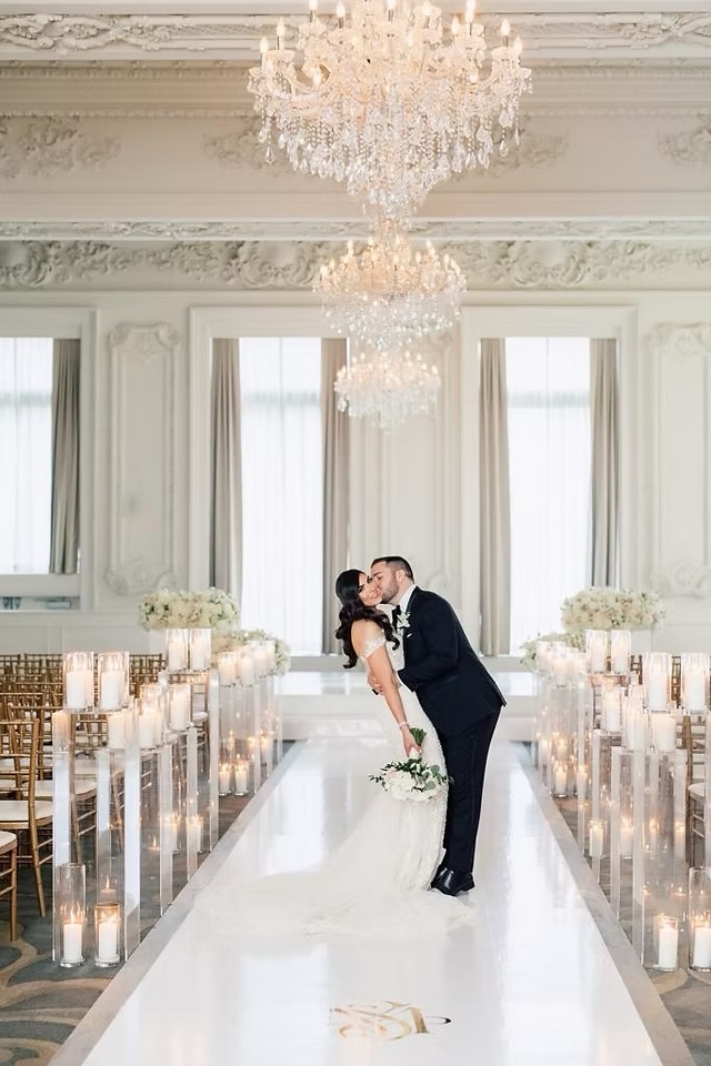 A luminous neutral ceremony aisle lined with pillar candles