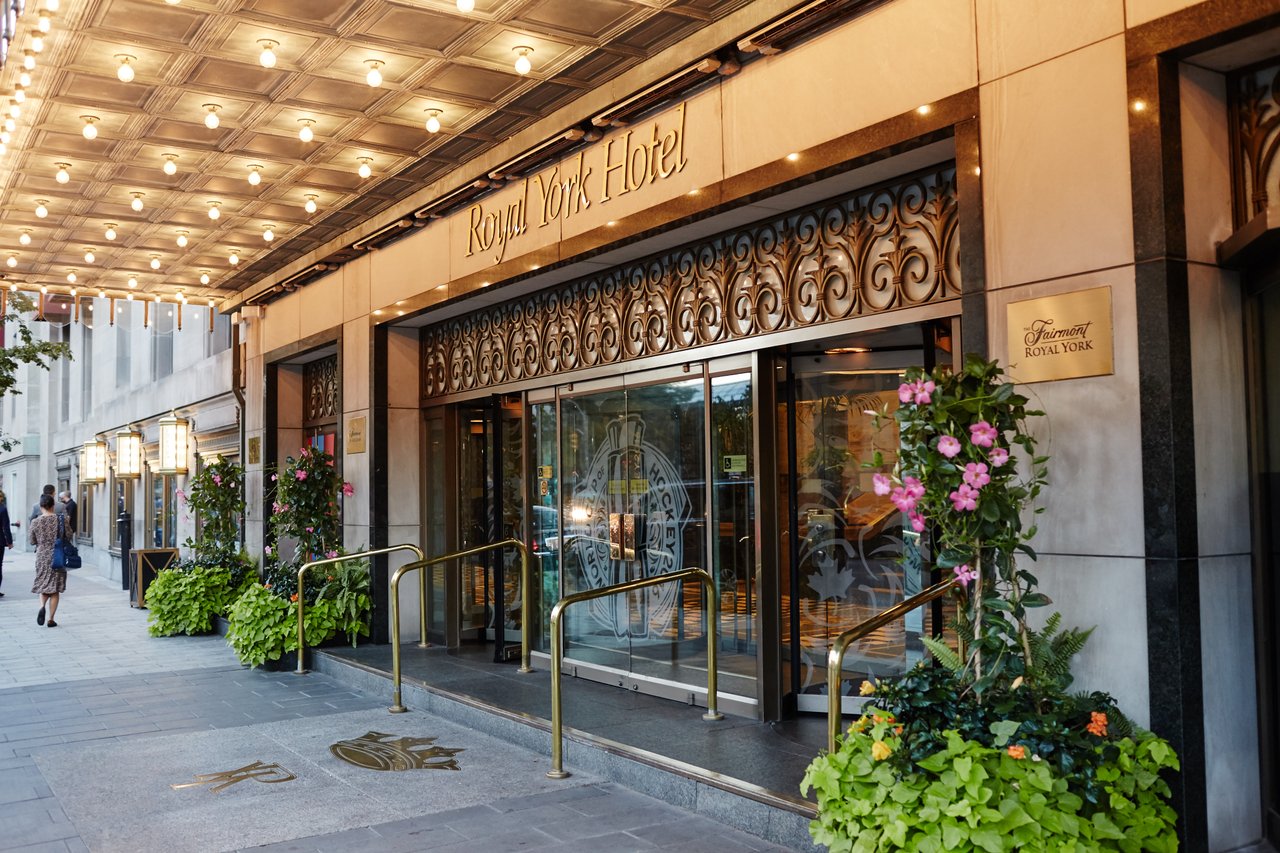Fairmont Royal York’s entrance with a glowing marquee, gold hotel lettering and flowering planters