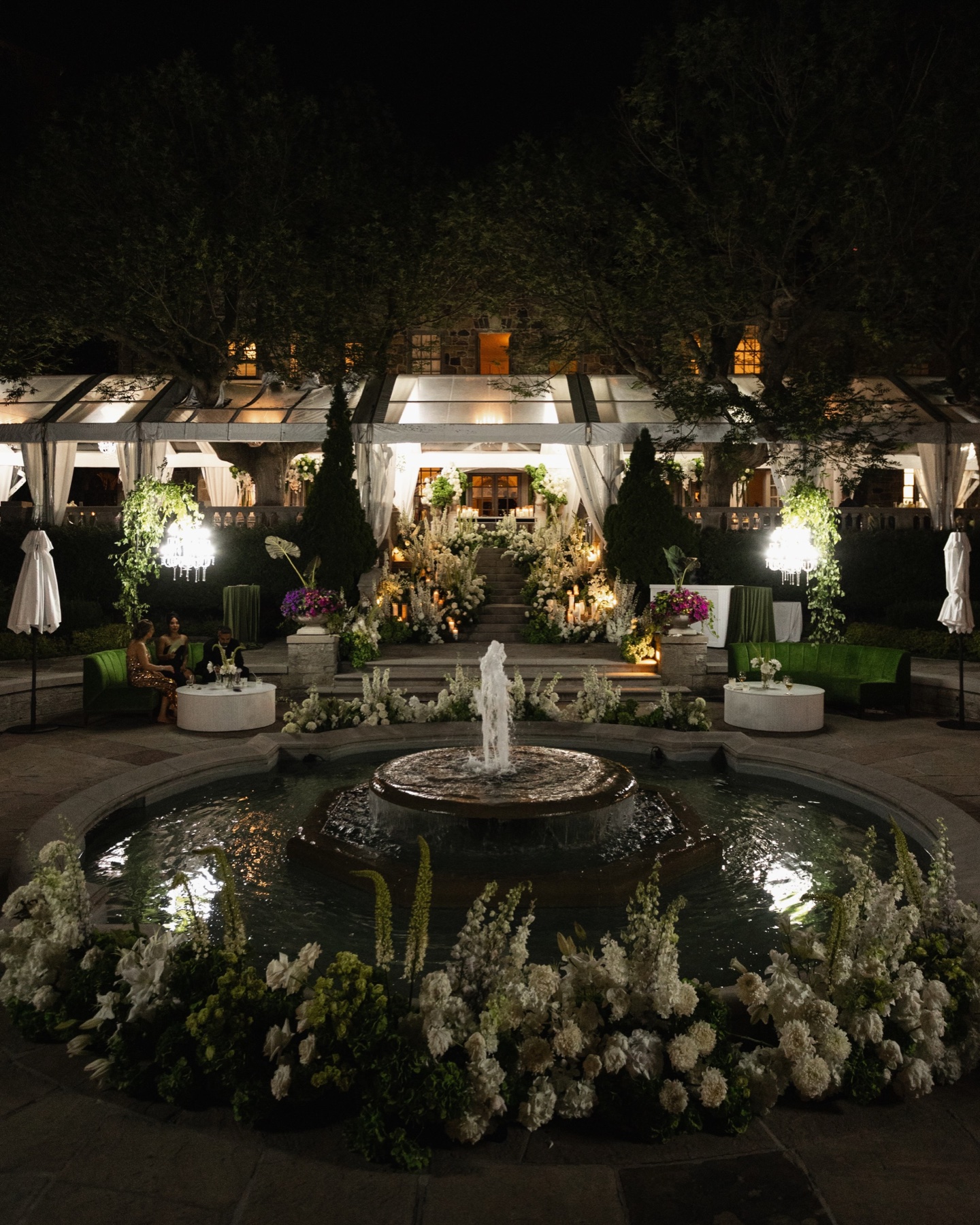 Graydon Hall Manor’s garden fountain at night with white flowers, candlelit steps and an illuminated pavilion