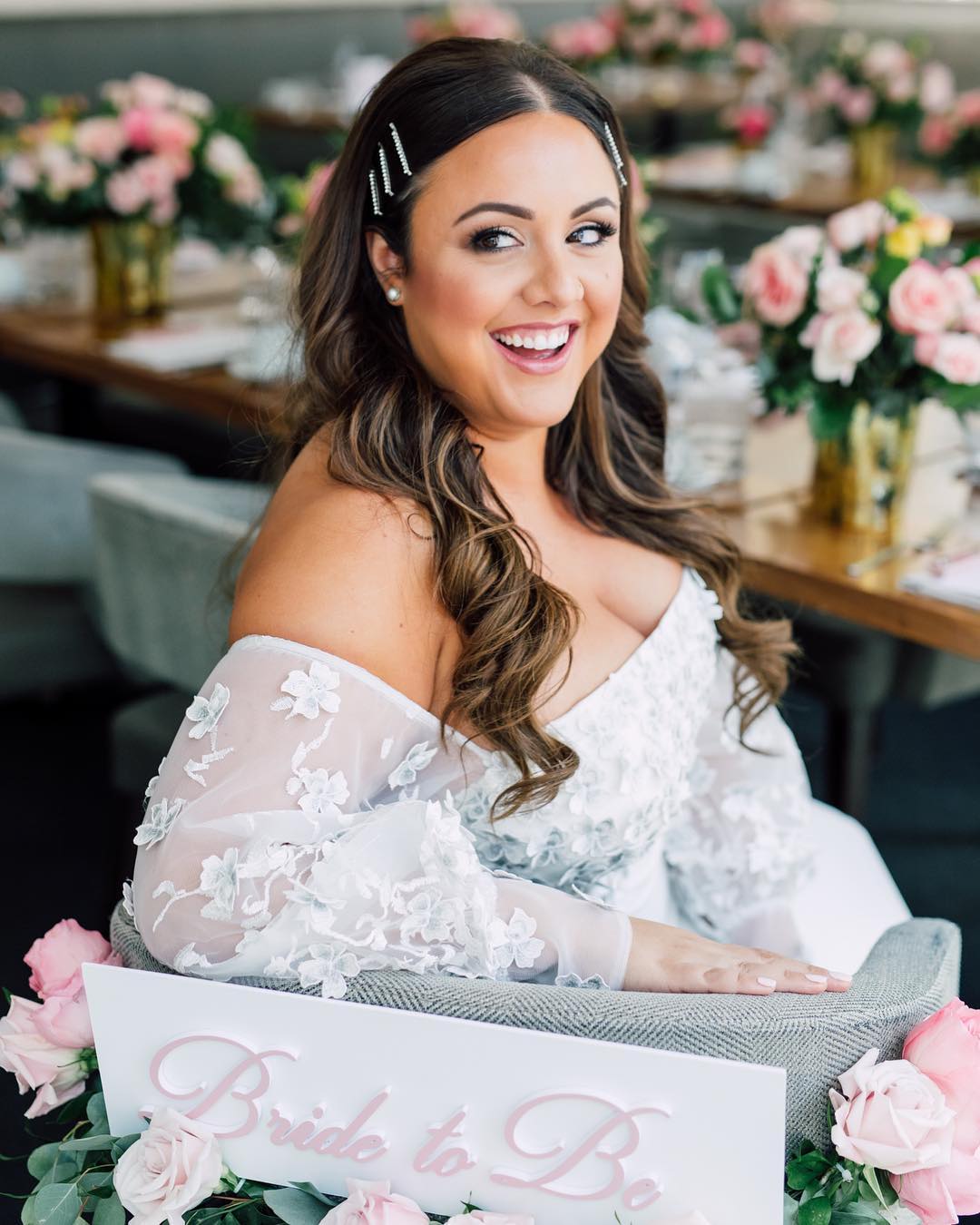 Bride-to-be Alexia seated among soft pink garden flowers at her bridal shower