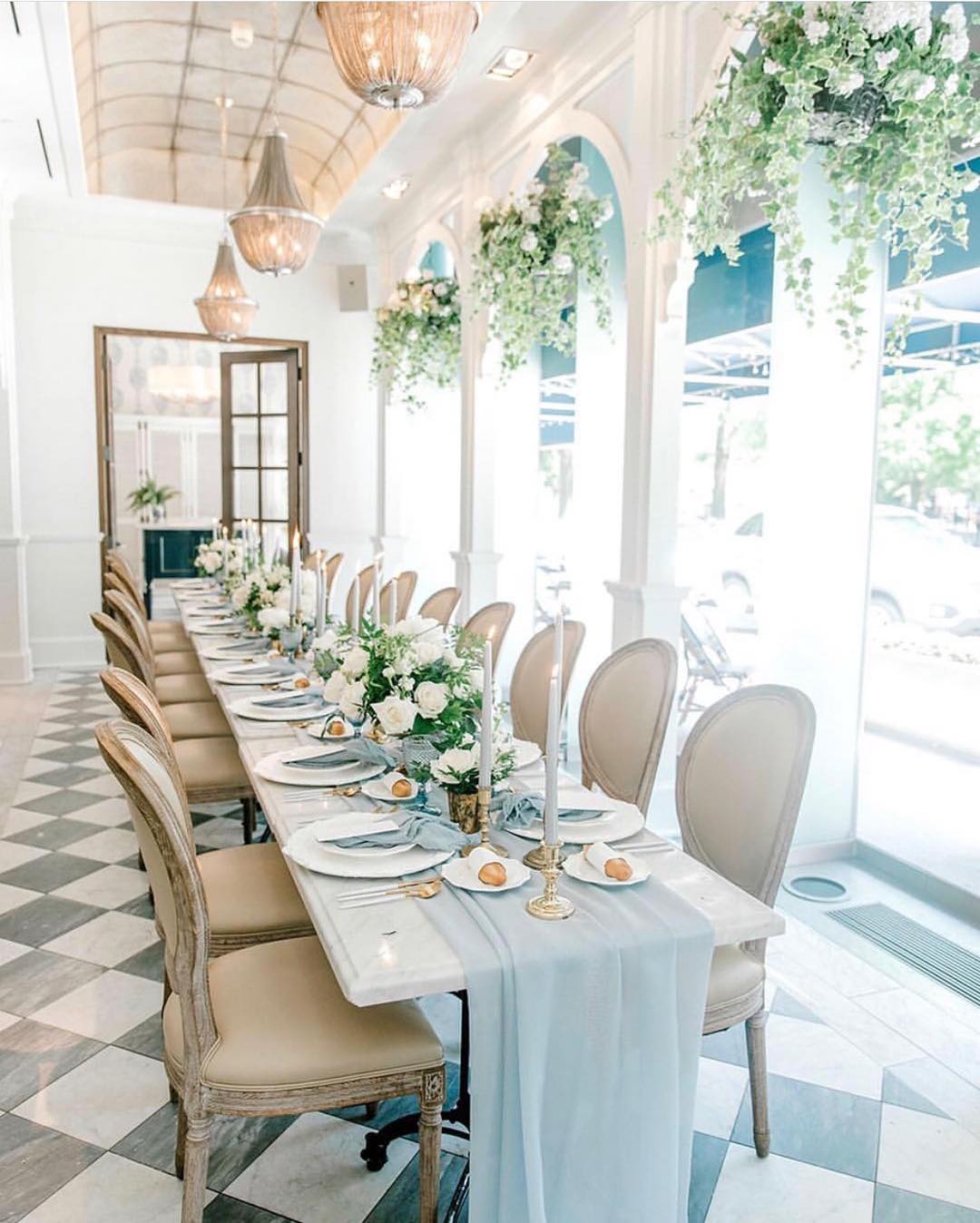 A long pale blue table beneath cascading greenery at a private baby shower
