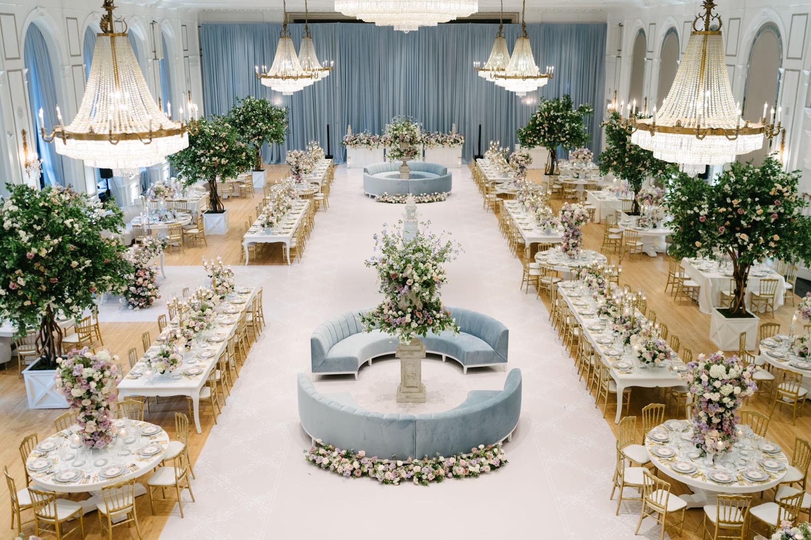 A sweeping view of the Fairmont ballroom filled with flowering trees, lavender blooms, and powder-blue lounge seating