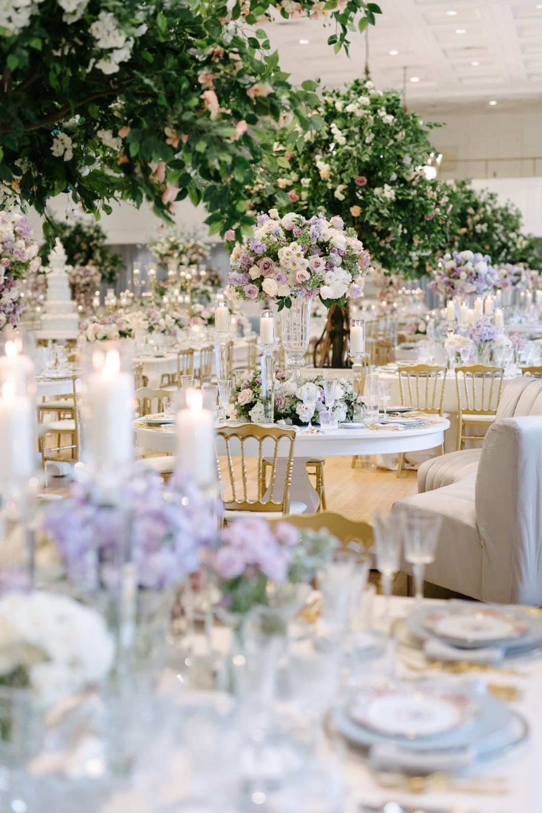 A round reception table framed by flowering trees and lavender centrepieces