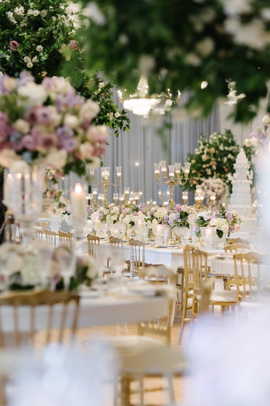 A candlelit reception table viewed through soft layers of garden flowers