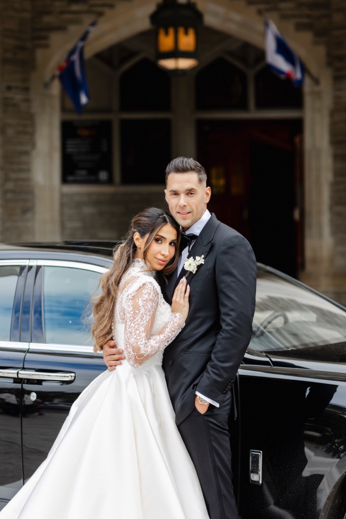 A portrait of a couple beside a black car at Casa Loma