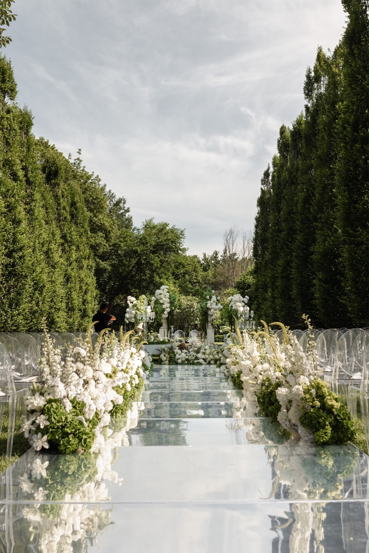 A mirrored garden ceremony aisle framed by white and green flowers