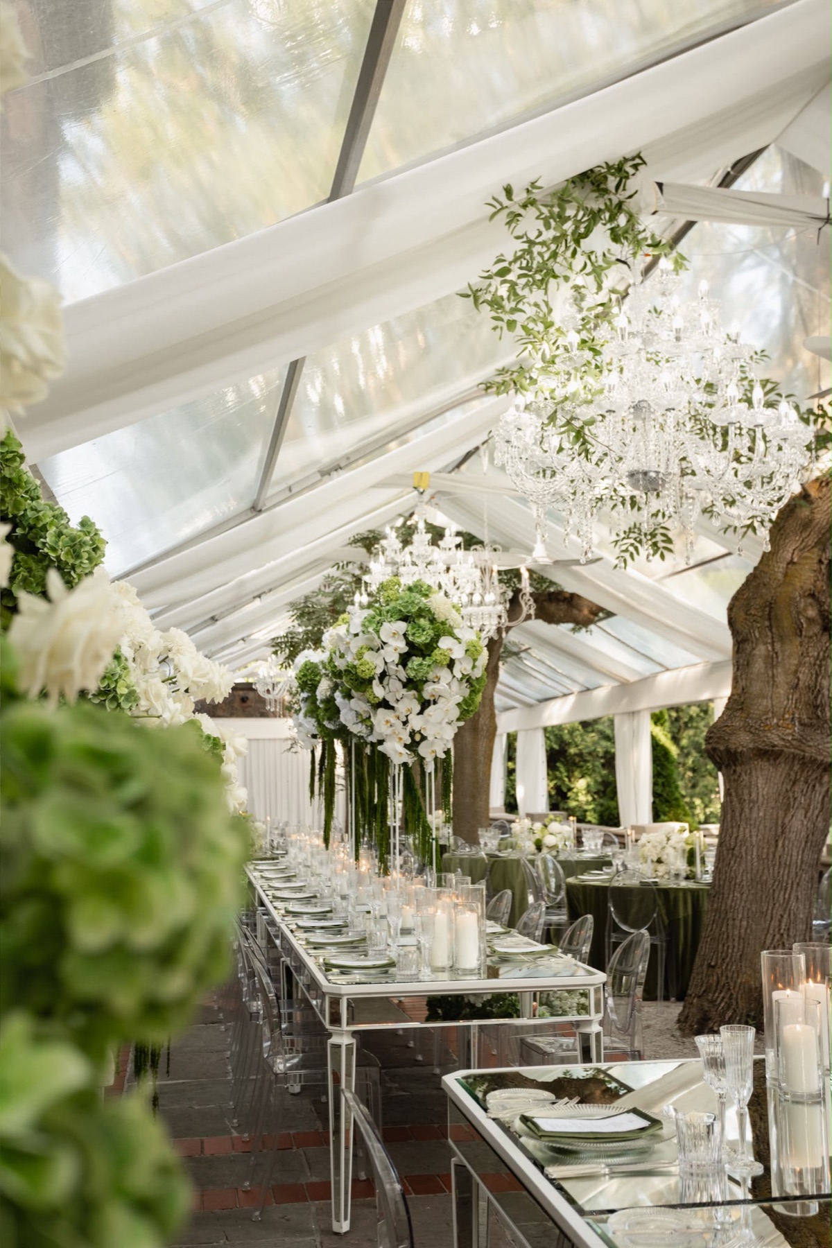 A glass garden pavilion with crystal chandeliers and green floral design