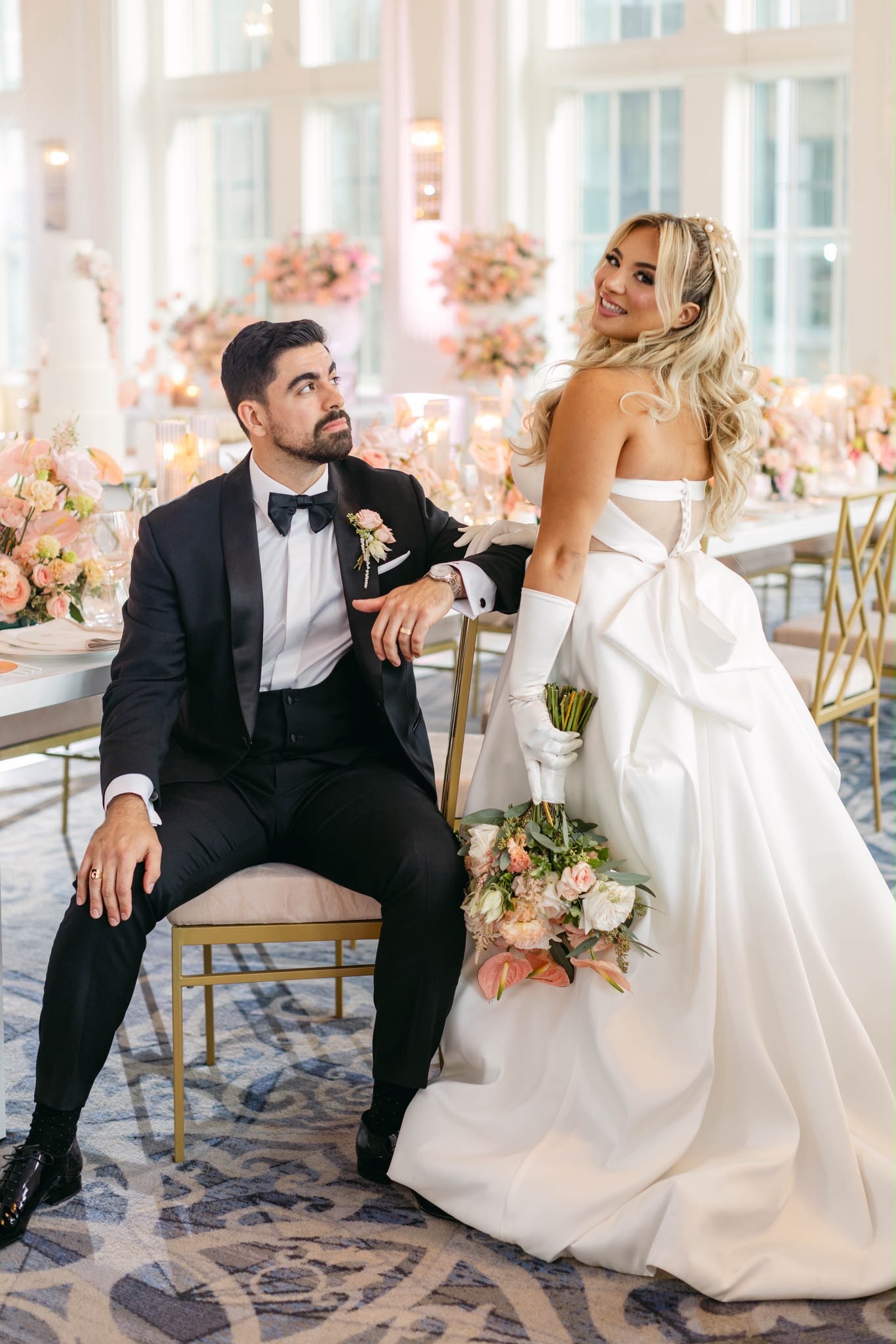 A couple in a light-filled reception layered with peach and blush flowers