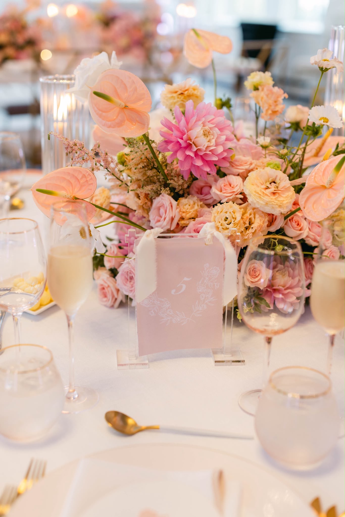 A reception table layered with peach anthuriums, blush roses, and candlelight