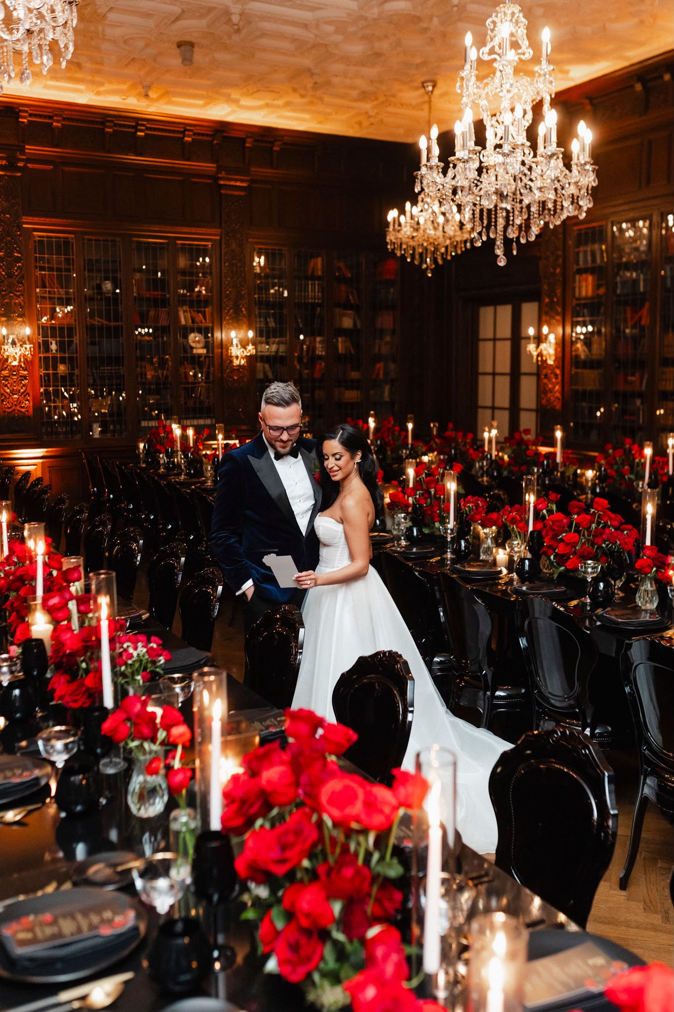 A couple in a candlelit Casa Loma library filled with red roses