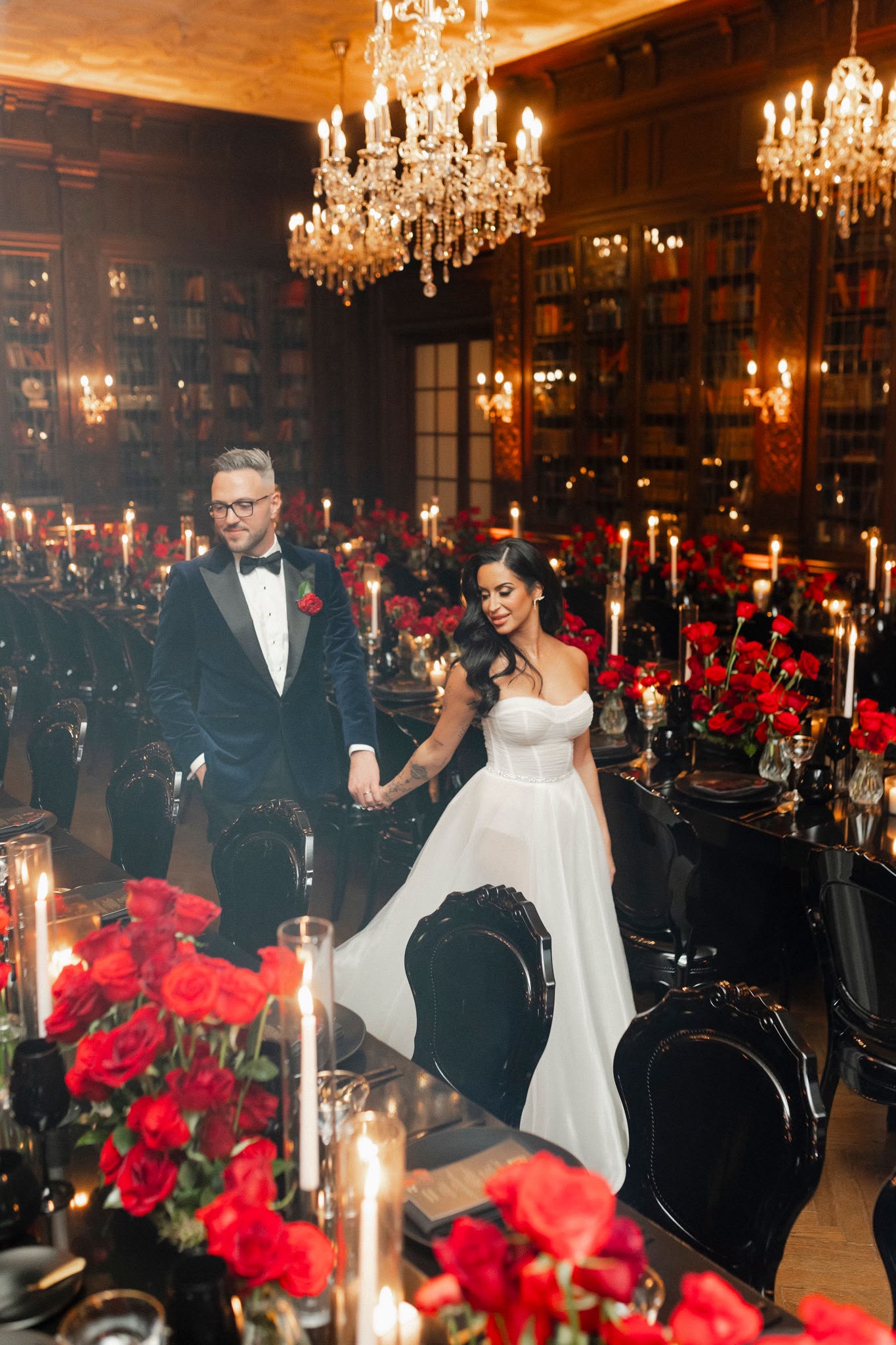 A couple walking hand in hand through the candlelit Casa Loma library