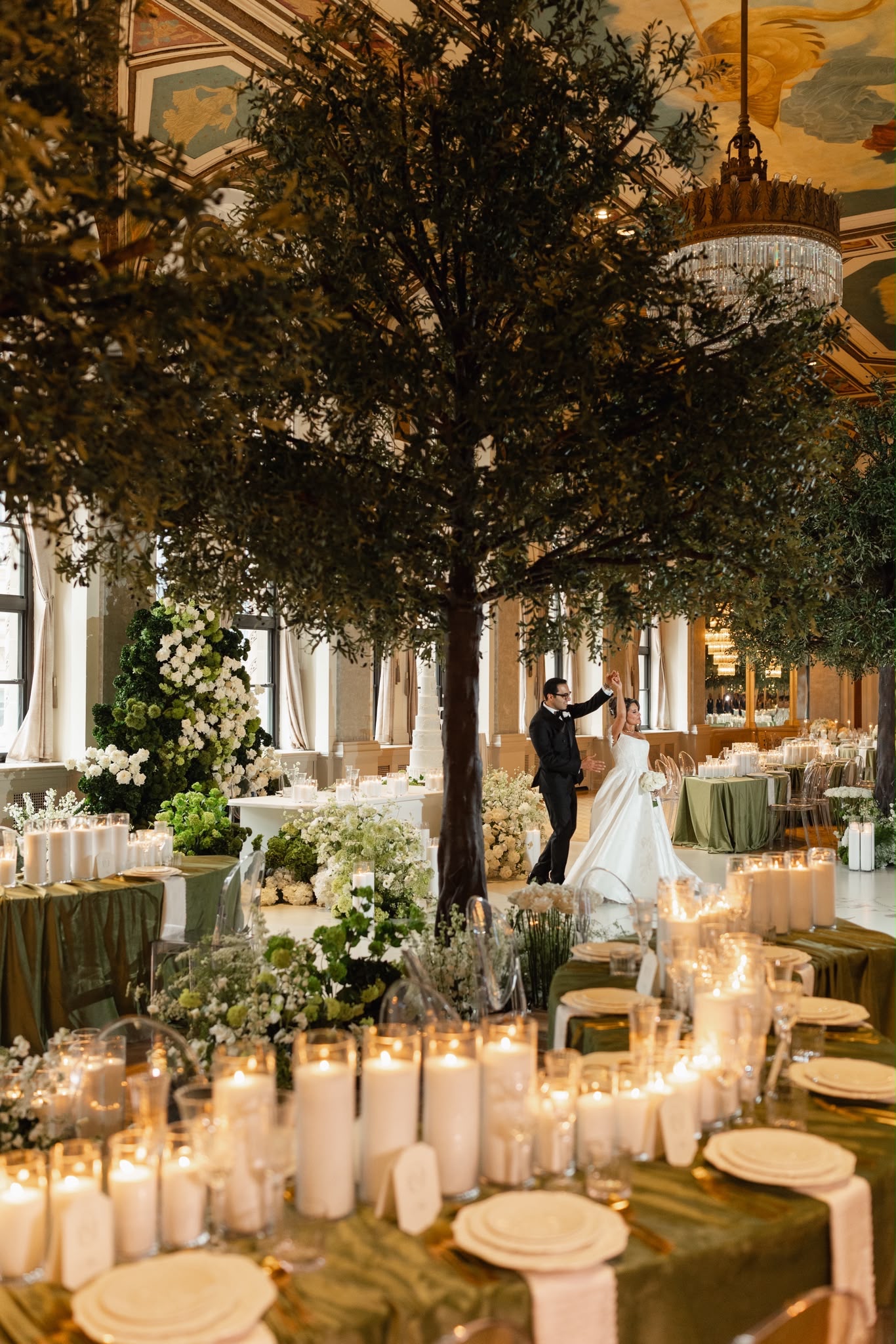 A candlelit Fairmont ballroom reception with olive trees, green tables, and white florals