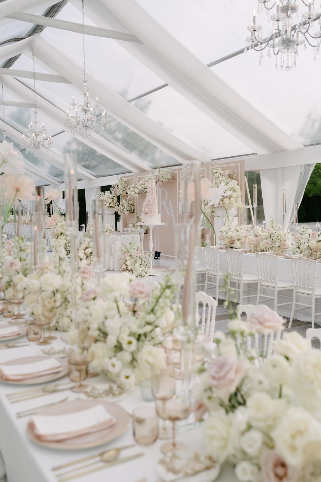 A luminous white pavilion filled with blush flowers and crystal chandeliers