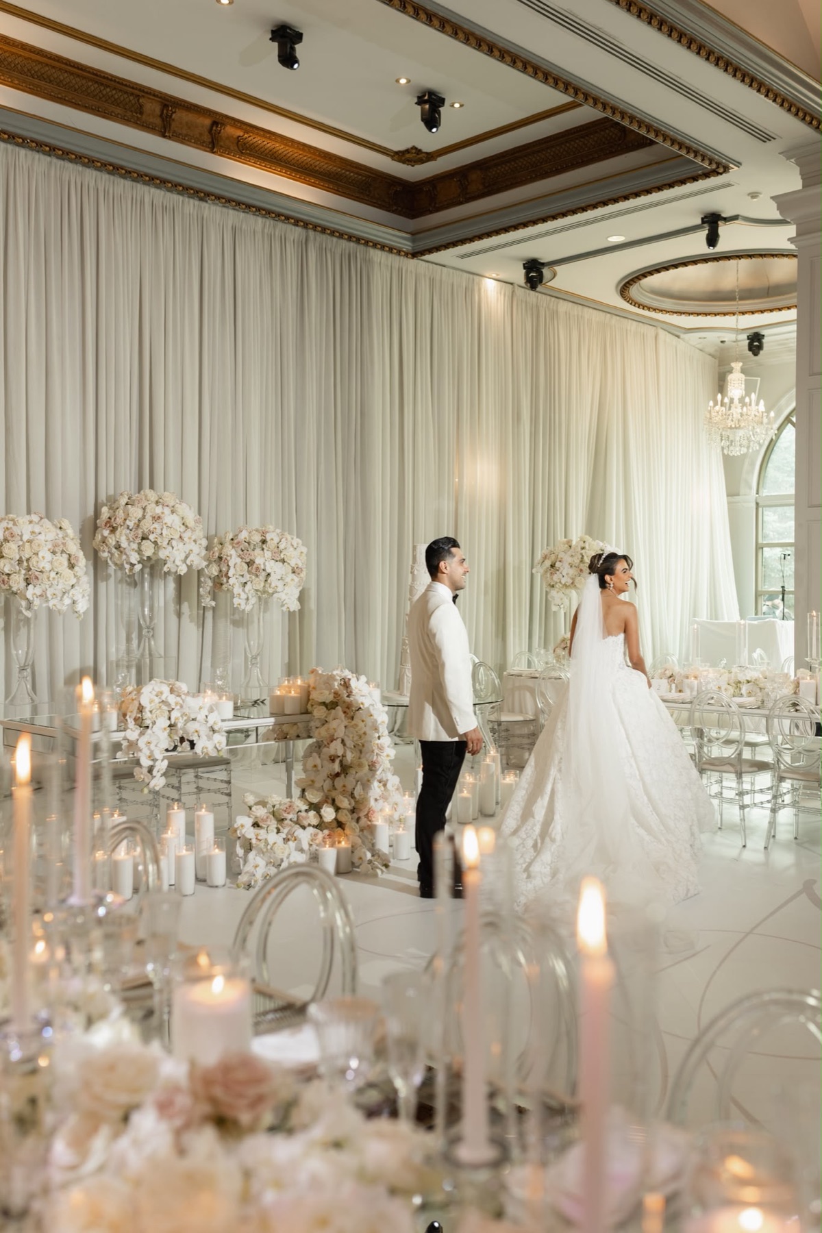A couple walking through a reception filled with orchids and candlelight