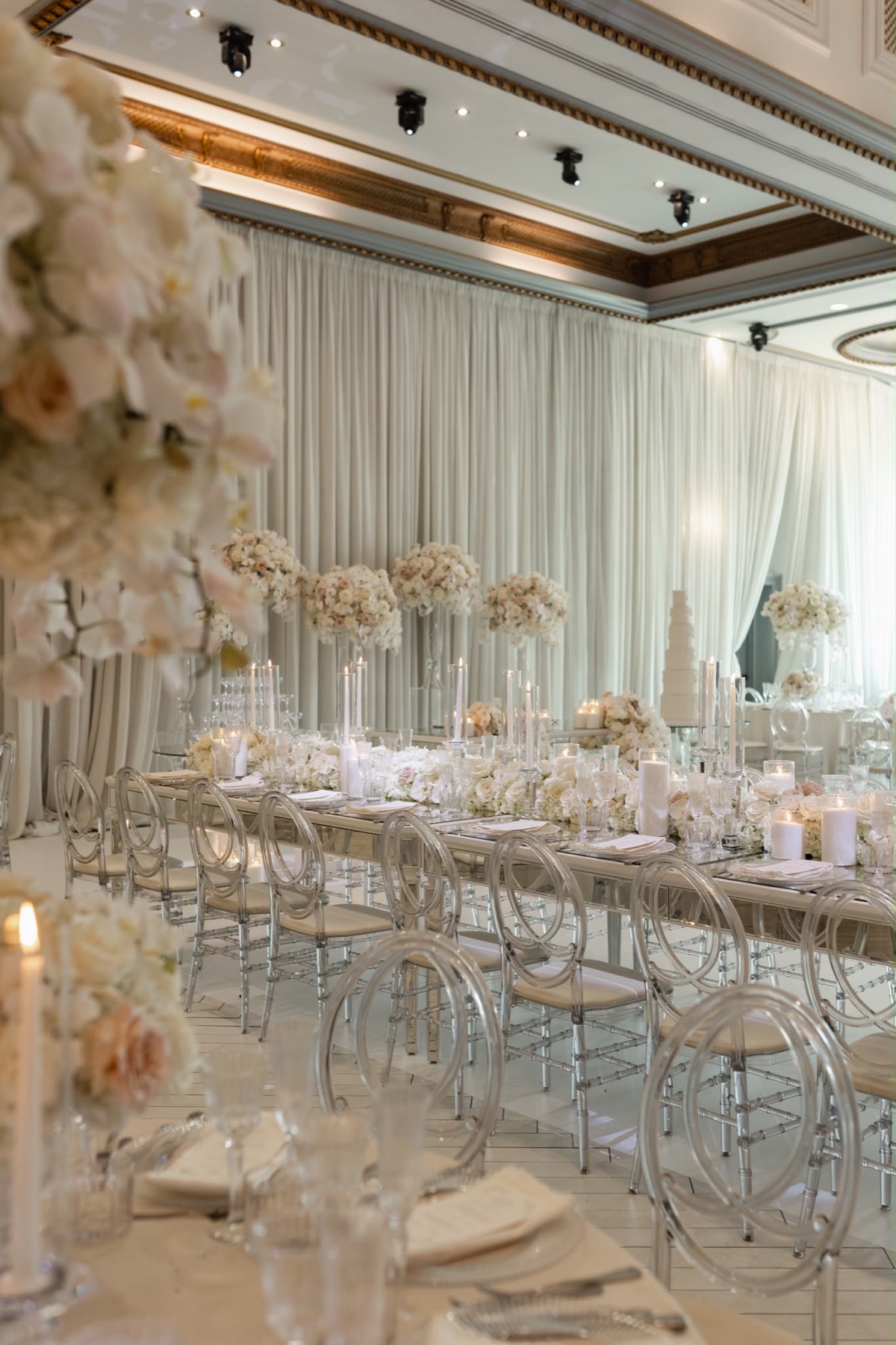 A long mirrored table surrounded by soft blush flowers and candlelight